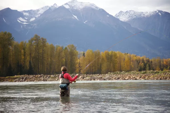 image of woman fly fishing on a lake with mountain