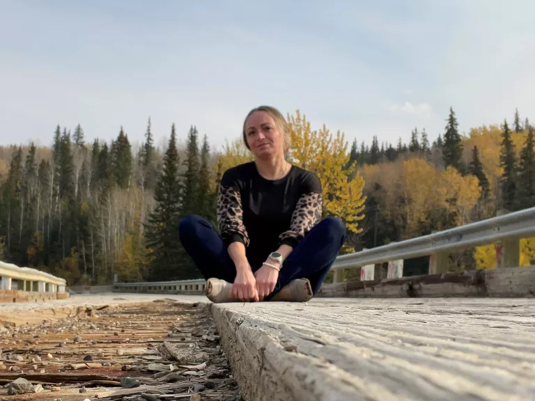 portrait of Kim sitting on railroad tracks on a sunny fall day